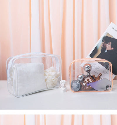 Two PVC transparent makeup bags in white and peach, one holding cotton pads and the other containing beauty tools, displayed on a white surface with a soft peach curtain background.