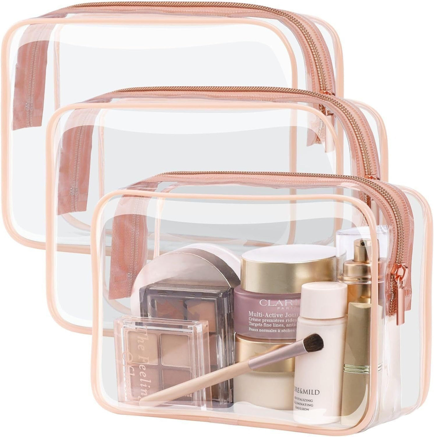 Set of three PVC transparent makeup bags with rose gold zippers, various sizes, holding cosmetic products and brush.